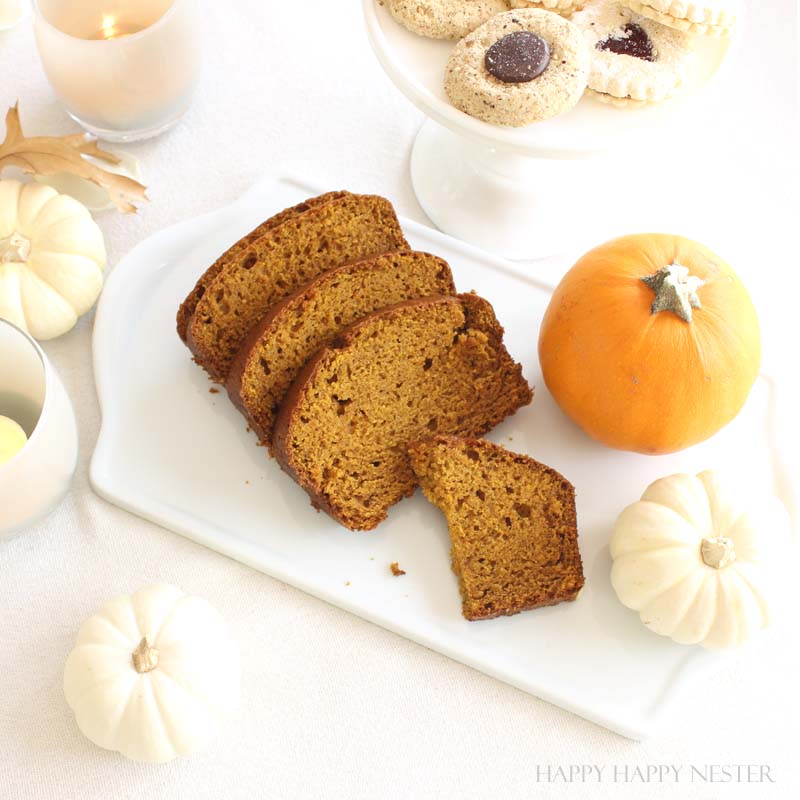 slices of pumpkin bread on a white platter with pumpkin surrounding it