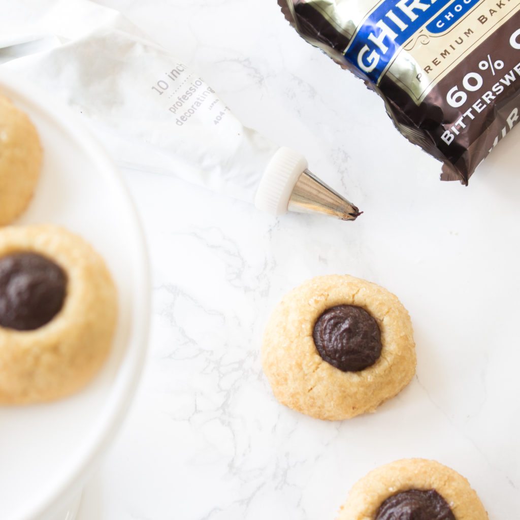 These wonderful Chocolate Thumbprint Cookies are rolled in turbinado sugar for a sweet crunchy outer layer. The chocolate ganache is a perfect pairing to the awesome little cookie. Baking | Cookie Recipe | Recipes | Desserts | Cookie | Chocolate Ganache | Cookies | Homemade Cookies | Best Cookies | Chocolate Cookie