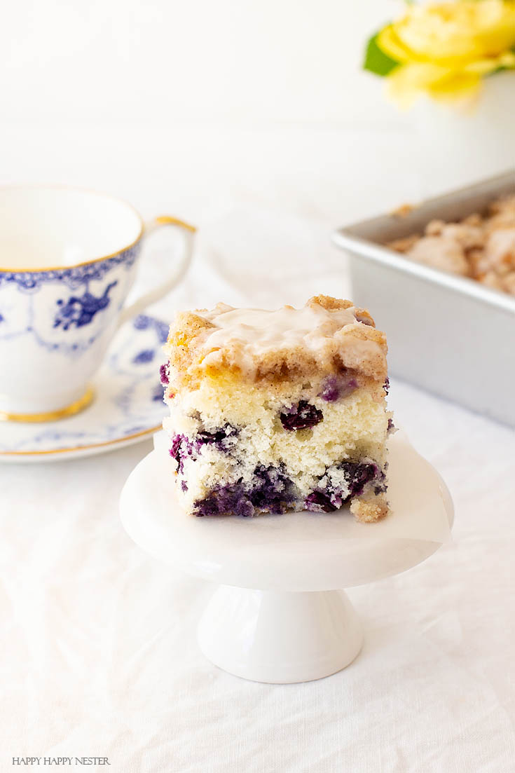 Blueberry cakes are so delicious. This dessert is The Best Blueberry Buckle Cake Recipe and is sure the perfect side to a cup of coffee or tea. Serve it as a dessert or as a morning blueberry coffee cake. This easy recipe makes an impressive cake with the crumble and delicious icing. #cake #coffeecake #blueberrydessserts #blueberries #desserts #pastry 