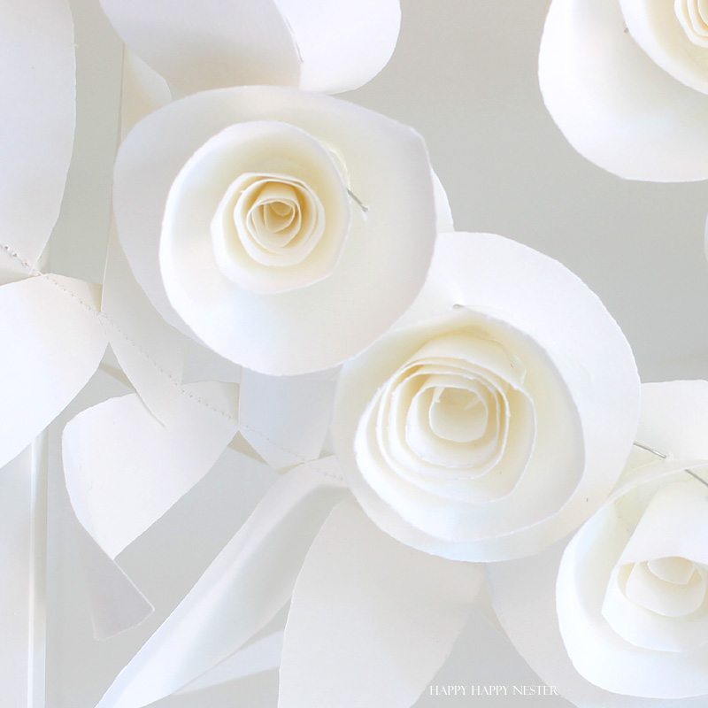 This fun paper garland DIY is not to be missed. You'll want to make both the leaf and rosettes garlands that you can hang anywhere in your home. Instant beauty wherever you place them. #craft #papercraft #paperflowers #garland #papergarland #weddingdecor #wedding