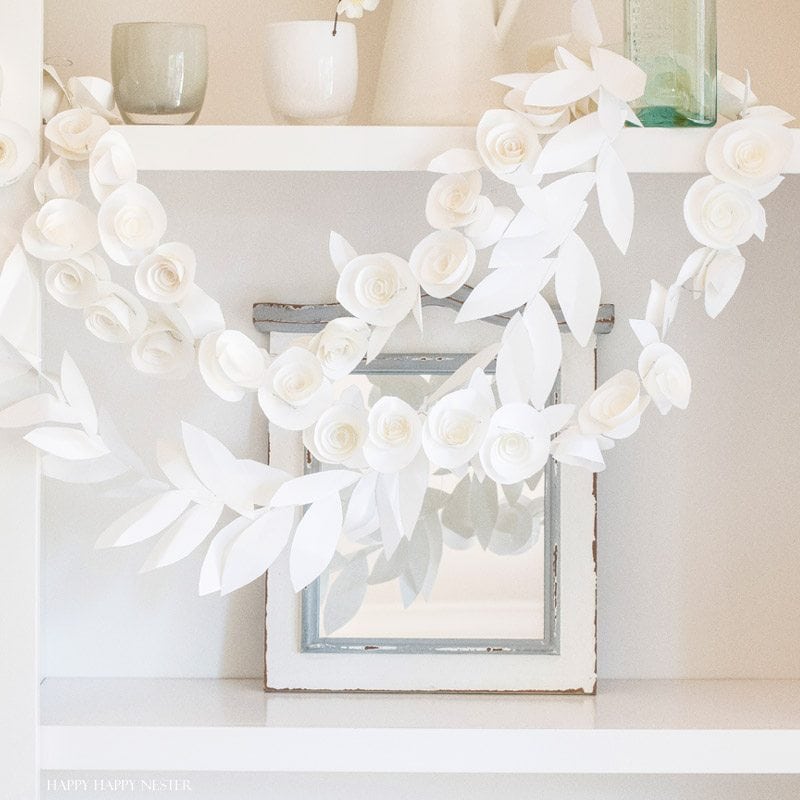 This fun paper garland DIY is not to be missed. You'll want to make both the leaf and rosettes garlands that you can hang anywhere in your home. Instant beauty wherever you place them. #craft #papercraft #paperflowers #garland #papergarland #weddingdecor #wedding