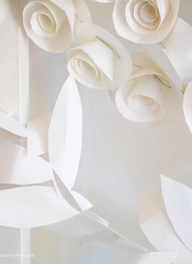 This fun paper garland DIY is not to be missed. You'll want to make both the leaf and rosettes garlands that you can hang anywhere in your home. Instant beauty wherever you place them. #craft #papercraft #paperflowers #garland #papergarland #weddingdecor #wedding