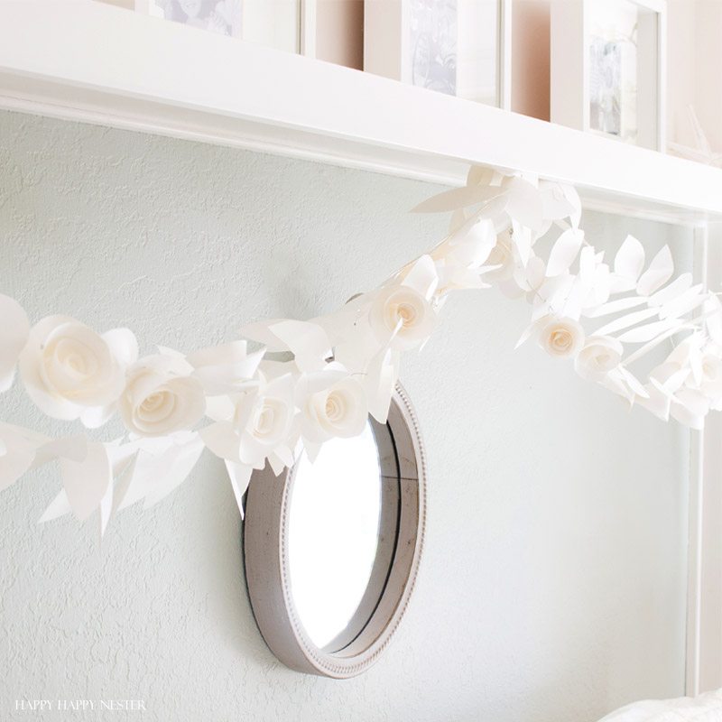 This fun paper garland DIY is not to be missed. You'll want to make both the leaf and rosettes garlands that you can hang anywhere in your home. Instant beauty wherever you place them. #craft #papercraft #paperflowers #garland #papergarland #weddingdecor #wedding