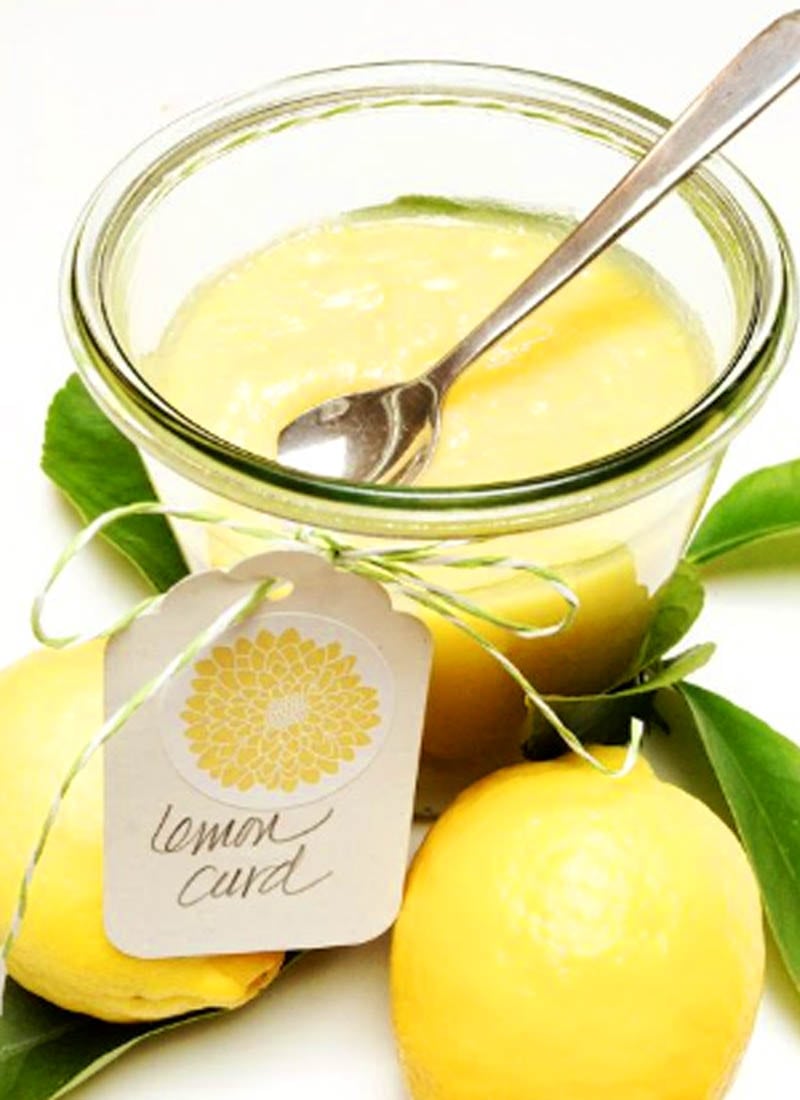 English Lemon Curd in glass container with lemons surrounding it