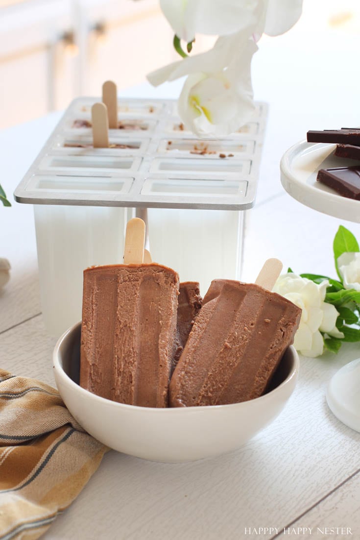 3 homemade Popsicles in bowl with popsicle mold in the backgroud