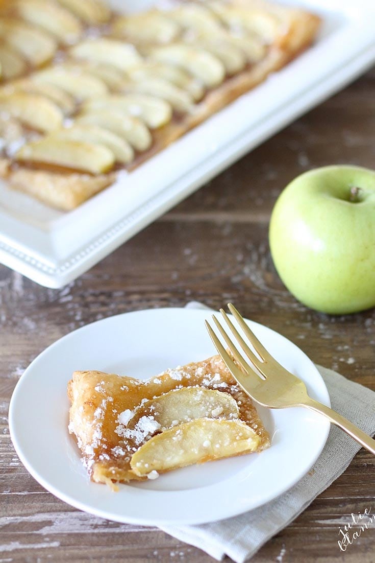 a slice of apple tart on a plate with a gold fork