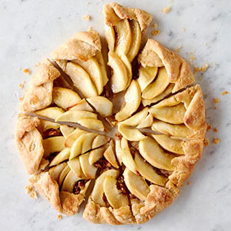 rustic apple tart with crumbs on a marble countertop