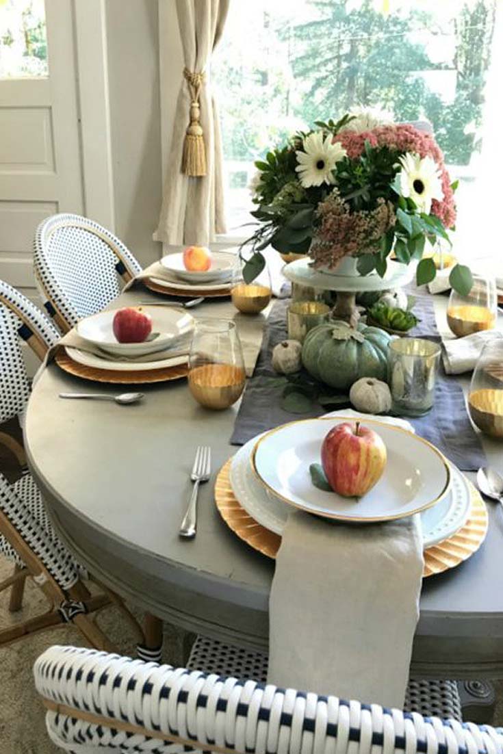 fall flowers in a vase on a table with apples on each place setting