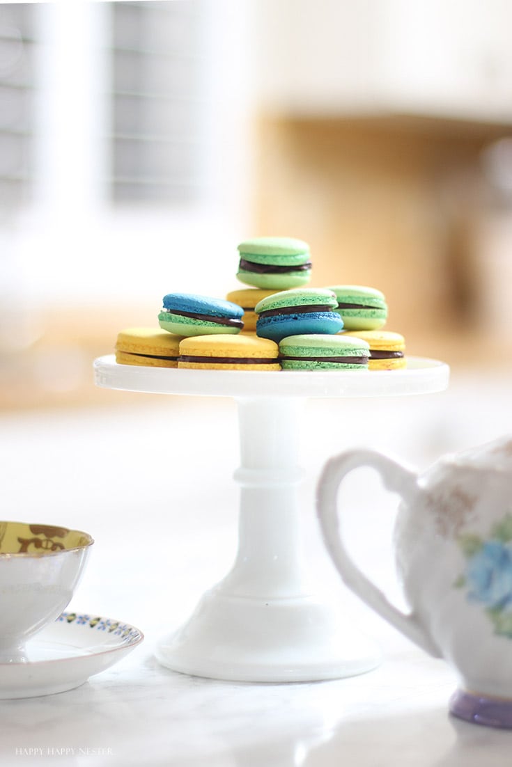 green and yellow macaron cookies on a white cake stand