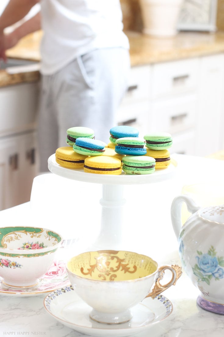 macaron cookies on a white cake stand in a white kitchen