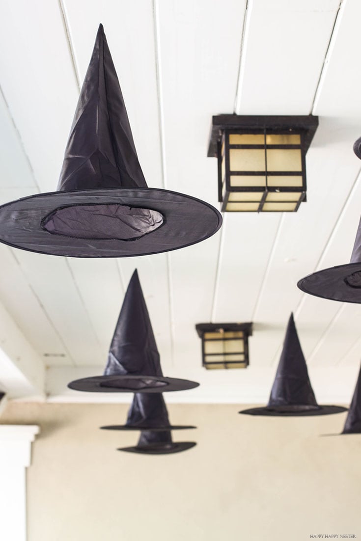 black witches hats hanging from an outdoor porch ceiling