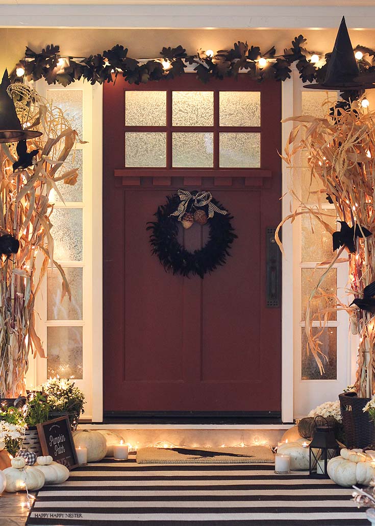 front red door with black feather wreath and white pumpkins on the ground. This a post about inexpensive Halloween front porch ideas