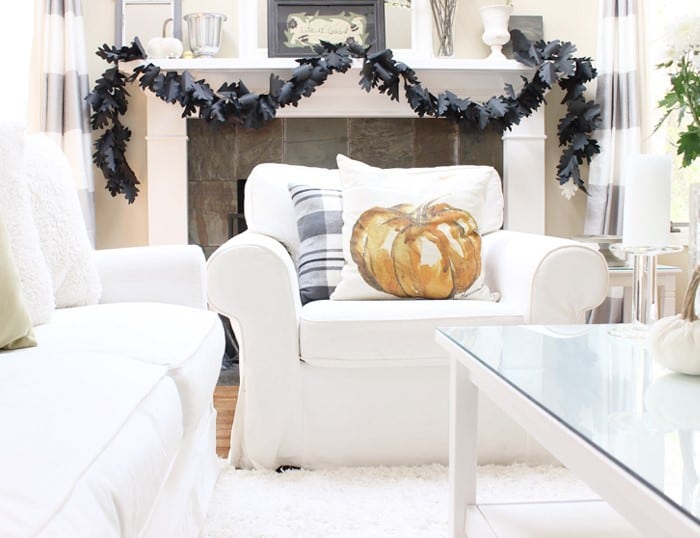 white living room with black leaf garland on mantel