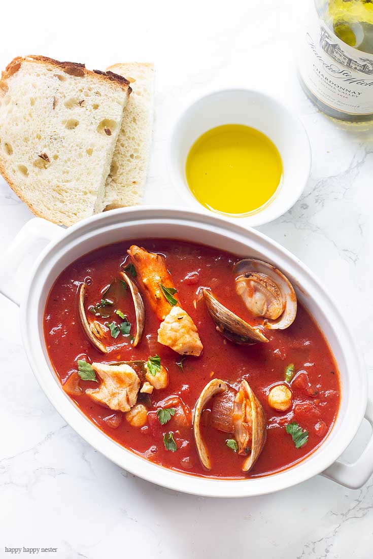 A loaf of sourdough and olive oil are great additions to this post of Cioppino. Our family favorite Yummy Seafood Stew Recipe is the best San Francisco style Cioppino. Make this the evening before so all the flavors are their best. This is the best Cioppino recipe since it includes wine and sugar to balance and mellow the acid from the tomatoes. #cioppino #italiandinner #soup #fishstew