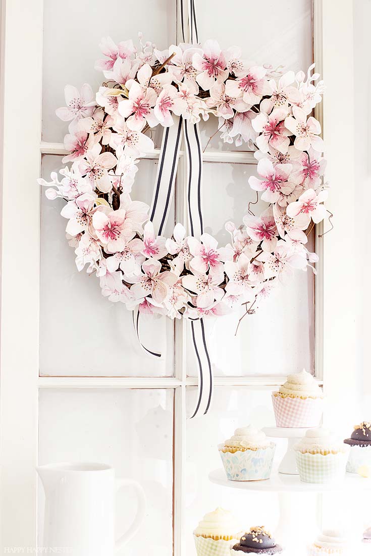 This easy How to Make a Paper Flower Wreath DIY is perfect for the spring. This wreath uses watercolor cherry blossoms that you cut out and glue to a grapevine wreath. It is a simple wreath that is beautiful and nice year round. The supplies include a wreath, paper, scissors, glue, and ribbon. #crafts #wreaths #spring