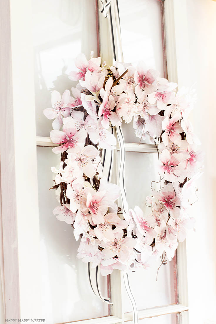 Paper flowers are perfect additions to a wreath. This easy How to Make a Paper Flower Wreath DIY is perfect for the spring. This wreath uses watercolor cherry blossoms that you cut out and glue to a grapevine wreath. It is a simple wreath that is beautiful and nice year round. The supplies include a wreath, paper, scissors, glue, and ribbon. #crafts #wreaths #spring