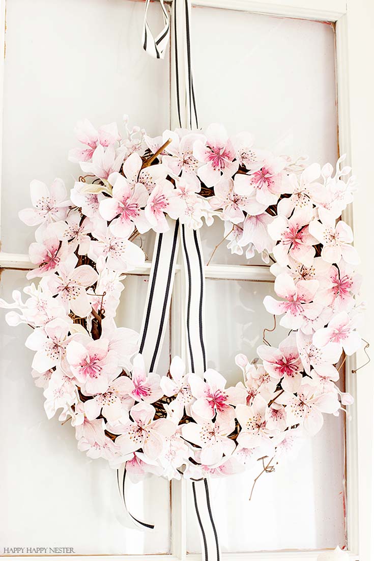 This easy How to Make a Paper Flower Wreath DIY is perfect for the spring. This wreath uses watercolor cherry blossoms that you cut out and glue to a grapevine wreath. It is a simple wreath that is beautiful and nice year round. The supplies include a wreath, paper, scissors, glue, and ribbon. #crafts #wreaths #spring