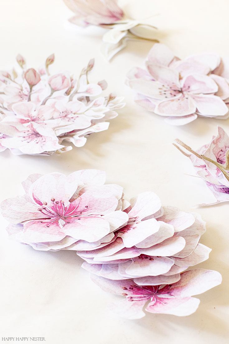 Get these free printable cherry blossom flowers for your wreath. This easy How to Make a Paper Flower Wreath DIY is perfect for the spring. This wreath uses watercolor cherry blossoms that you cut out and glue to a grapevine wreath. It is a simple wreath that is beautiful and nice year round. The supplies include a wreath, paper, scissors, glue, and ribbon. #crafts #wreaths #spring
