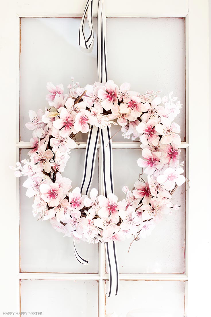 Make this floral paper wreath. This easy How to Make a Paper Flower Wreath DIY is perfect for the spring. This wreath uses watercolor cherry blossoms that you cut out and glue to a grapevine wreath. It is a simple wreath that is beautiful and nice year round. The supplies include a wreath, paper, scissors, glue, and ribbon. #crafts #wreaths #spring