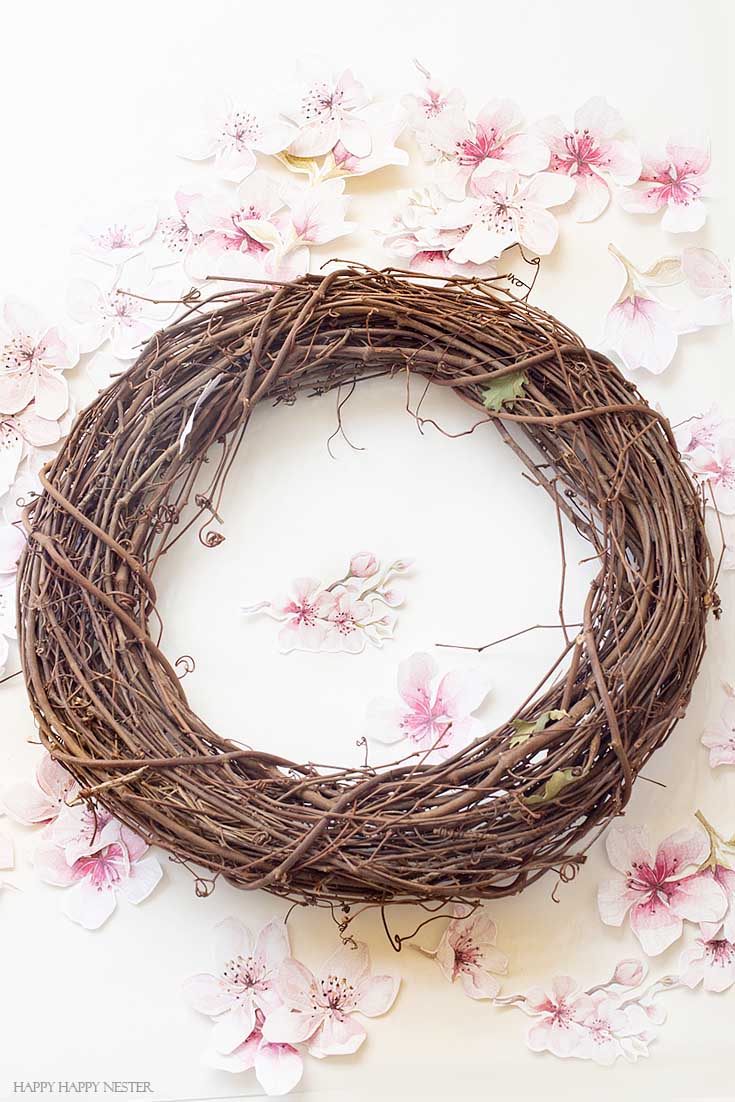 Love this grapevine wreath DIY. This easy How to Make a Paper Flower Wreath DIY is perfect for the spring. This wreath uses watercolor cherry blossoms that you cut out and glue to a grapevine wreath. It is a simple wreath that is beautiful and nice year round. The supplies include a wreath, paper, scissors, glue, and ribbon. #crafts #wreaths #spring