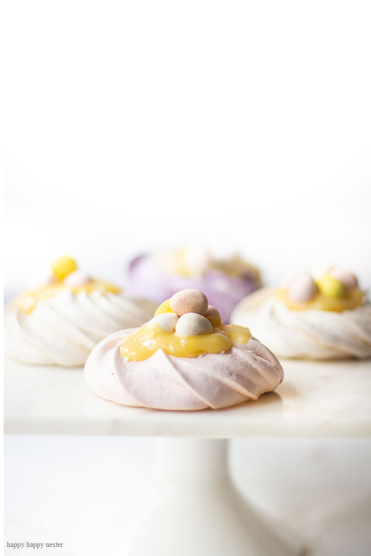 This is a great spring and summer dessert. This Pavlova Recipe is so easy and the Mini Nests are so adorable. They are perfect for Easter, a spring dessert or year-round treat. Use different food colors to create cute fresh nests. Top the nests with lemon curd, whip cream, and Easter eggs. #baking #easter #desserts #easterdesserts #meringue #pavlova #lemoncurd