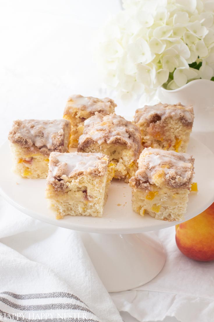 Here is the best ever peach buckle recipe and is the perfect summer dessert. This easy recipe is fresh and yummy with a cinnamon crumble and vanilla icing. Add a dollop of ice cream to accompany this summer cake. #recipes #peaches #freshfruitrecipes #desserts