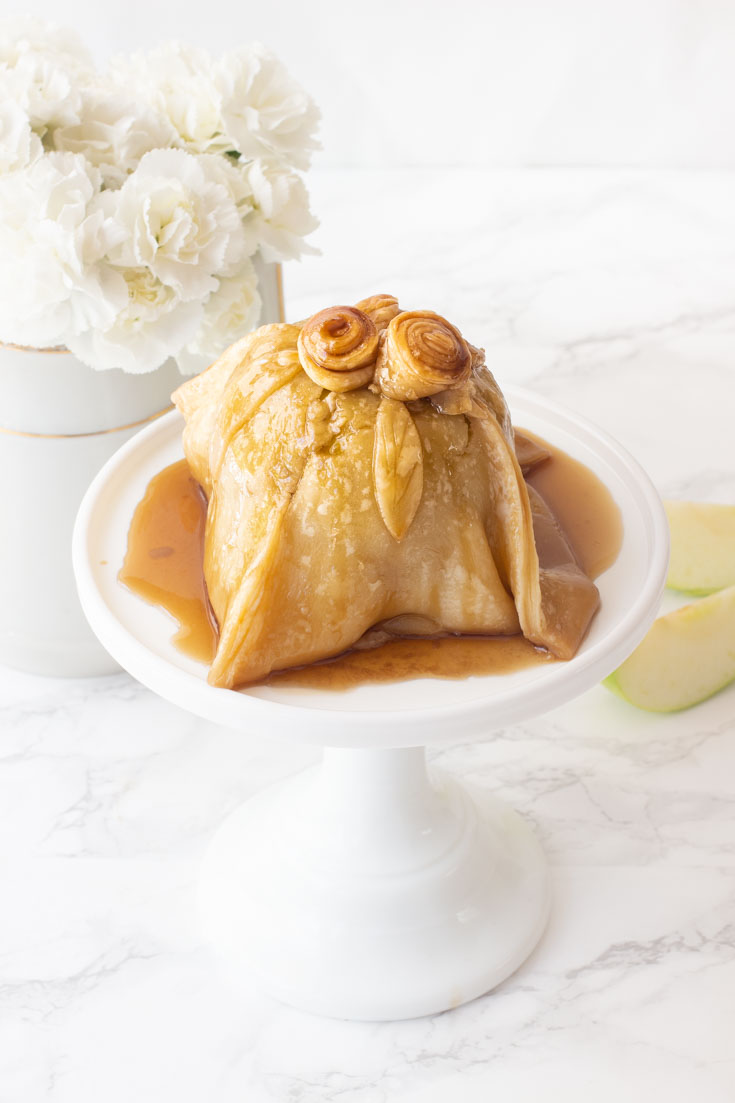 The apple is stuffed with sugared nuts inside the core and is topped with a pastry dough covered in a yummy caramel sauce. Use the ready-made pie crust to make this an easy and quick dessert. #dessert #appledumpling #appledesserts