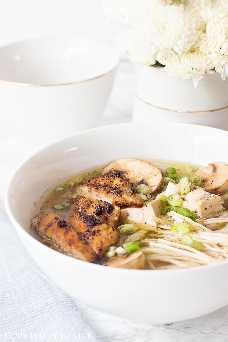 Homemade Chicken Noodles Soup in a big white bowl. This Homemade Chicken Noodle Soup goes beyond the traditional recipe. It uses the delicious Japanese Udon Noodles that make this broth utter perfection. Find the tasty thick udon noodles at your Asian grocery store. Learn how to make this wonderful comfort food recipe. #chickennoodlesoup #soup #udon #japanesecuisine