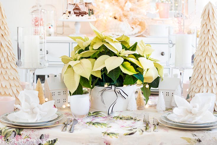 Use white Christmas poinsettias on your holiday tables. Find out these table ideas for Christmas decorating. This table decor is feminine and vintage all rolled up in one. #shabbychic #Christmasvintage #vintageornaments #whitepointsettias