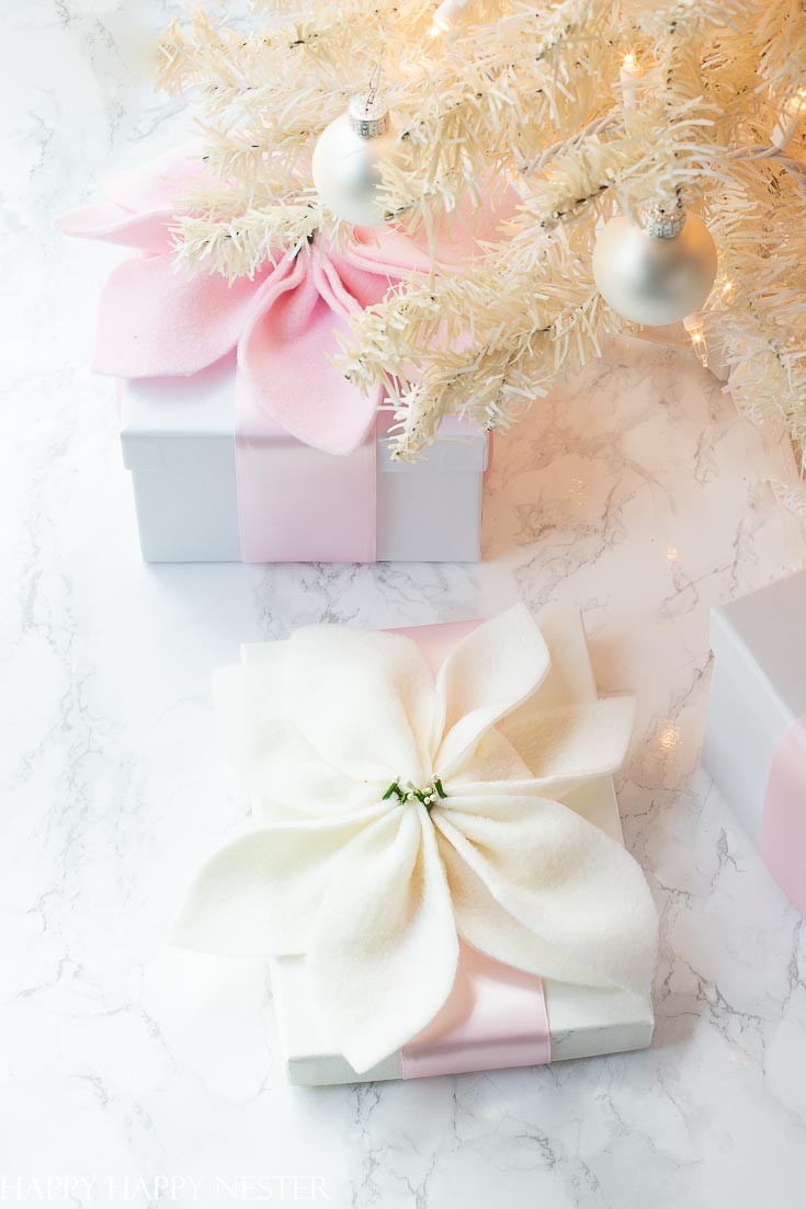 Have an extra fleece remnant? Make these cute fleece poinsettias. They are pretty on top of holiday gifts. This is an easy craft project that even your kids can make. #craftproject #poinsettias #flowerdiy #pinkflowers #fleececrafts #christmasprojects