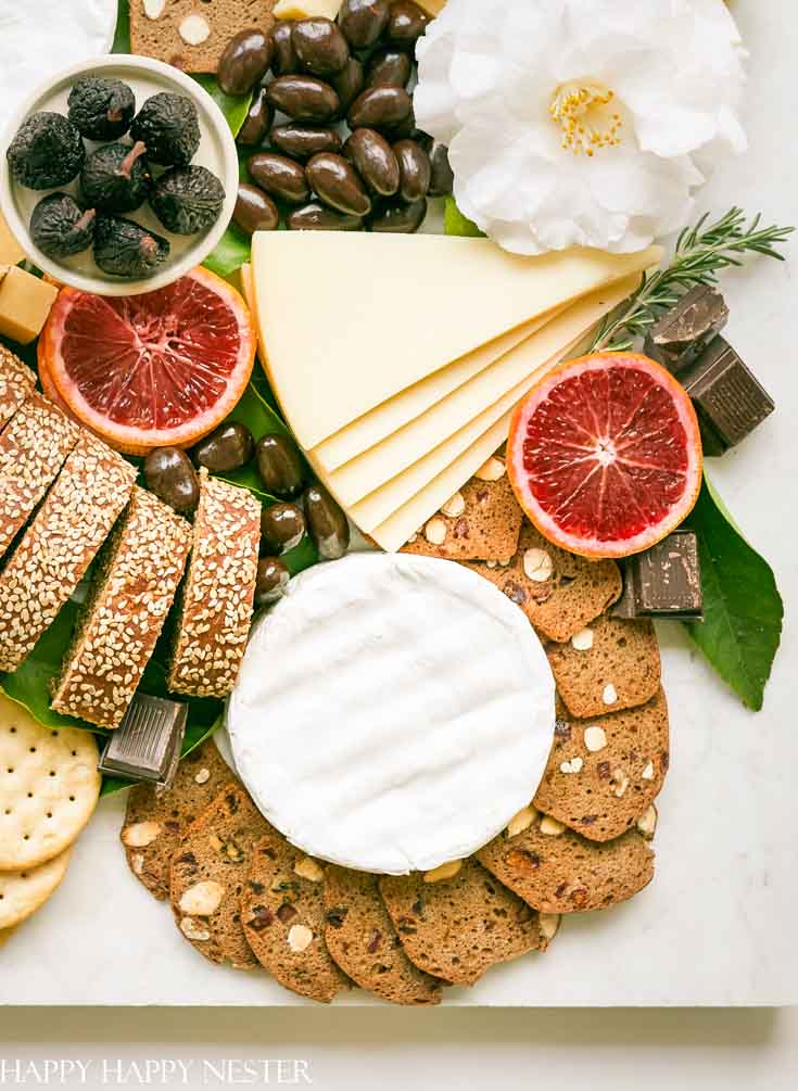 This impressive Charcuterie Board is elegantly styled with delicious cheeses, slices of bread, fruit, and chocolates. This epic appetizer will wow friends. Make this for any get together or meal. #charcuterieboard
