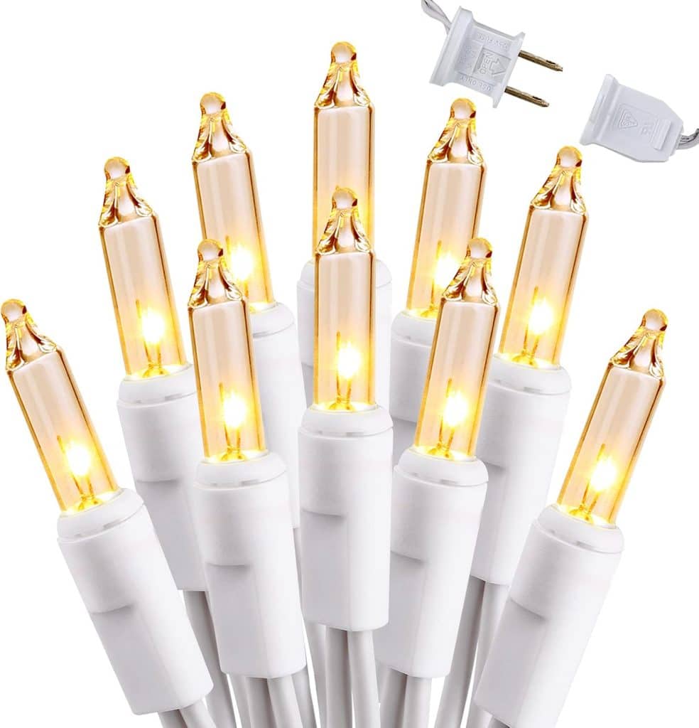 Close-up of glowing white Christmas string lights—with mini incandescent bulbs and a white two-prong plug—perfect for illuminating your red and white Christmas tree. The lights are grouped together, emitting a warm yellow-orange glow that beautifully complements festive holiday decor.