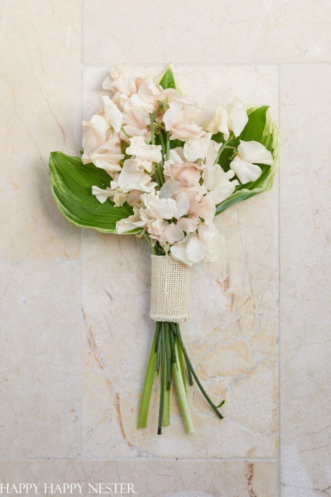 small bouquet of flowers with pale pink sweet peas and hosta leaves