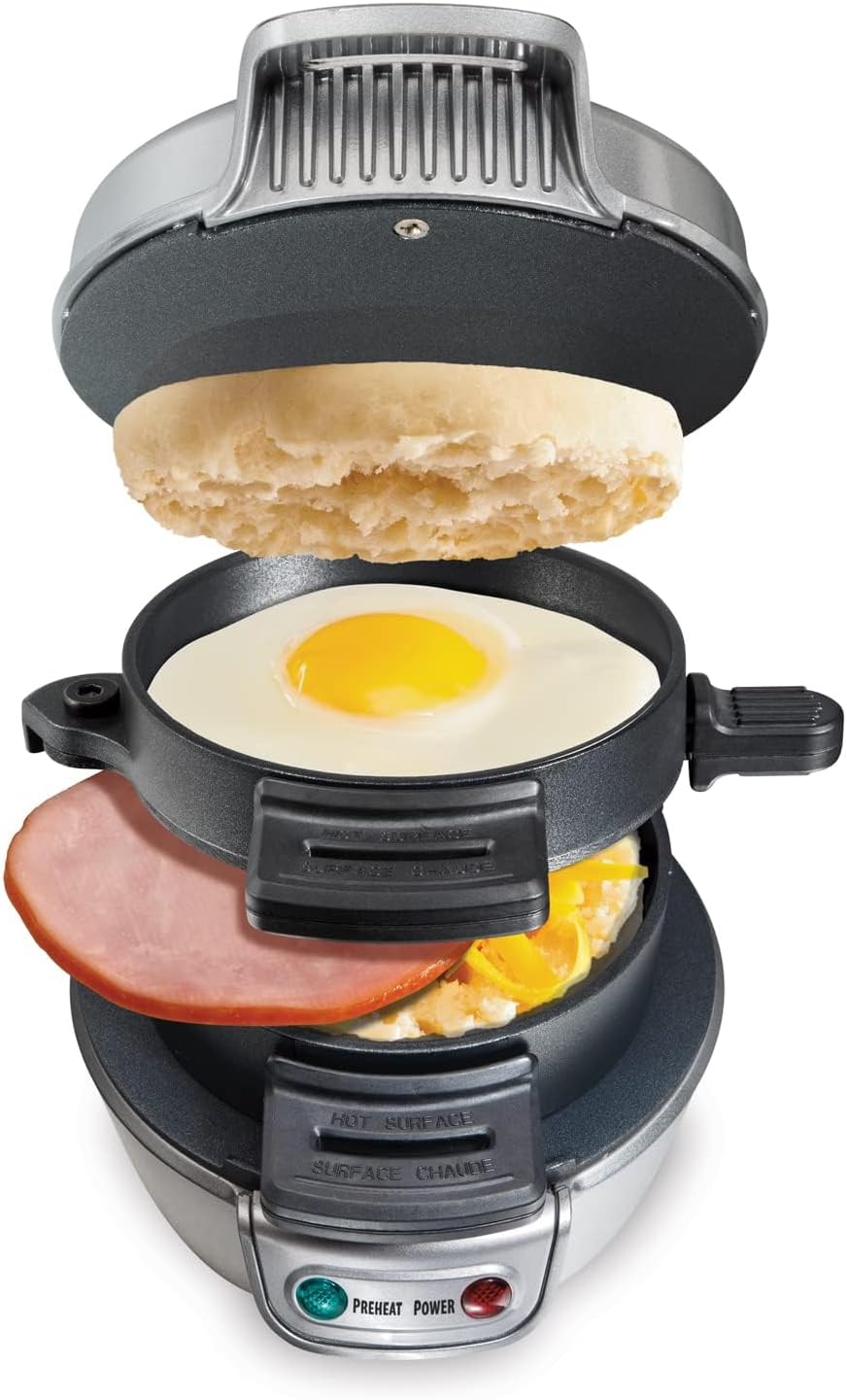 A breakfast sandwich maker with separate compartments, shown open and layered with an English muffin, a fried egg, cheese, and ham—perfect for creating the best recipes for breakfast. The appliance features indicator lights on the front.