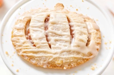 Mini pumpkin hand pie with icing drizzle on a white cake stand