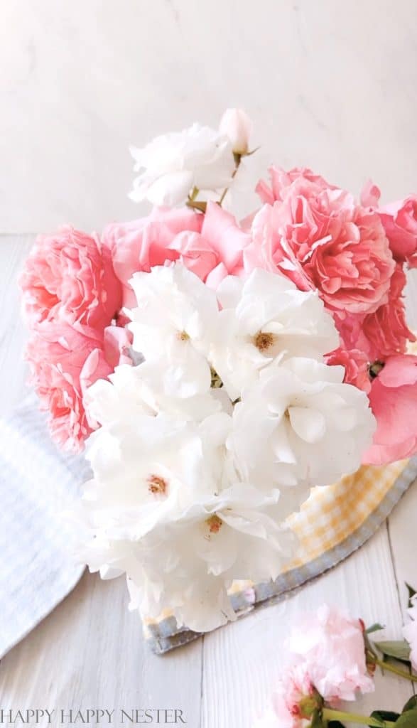 This photo show pink and white roses in a vase and it shows how to create a peony arrangement.