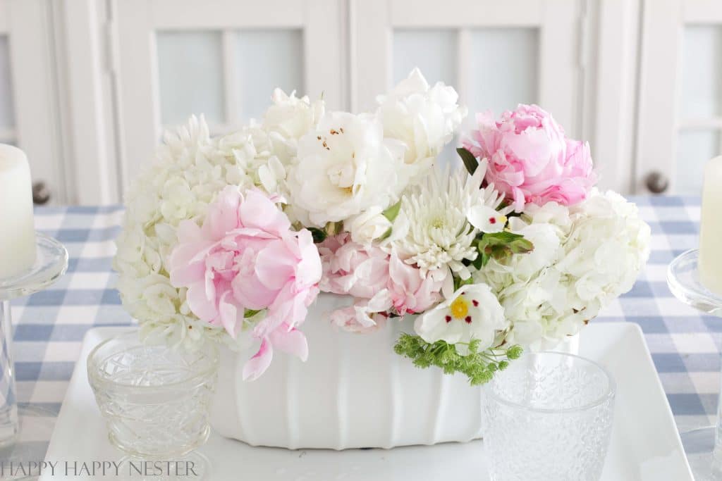 pink peonies and white roses in a white vase on a dining room table