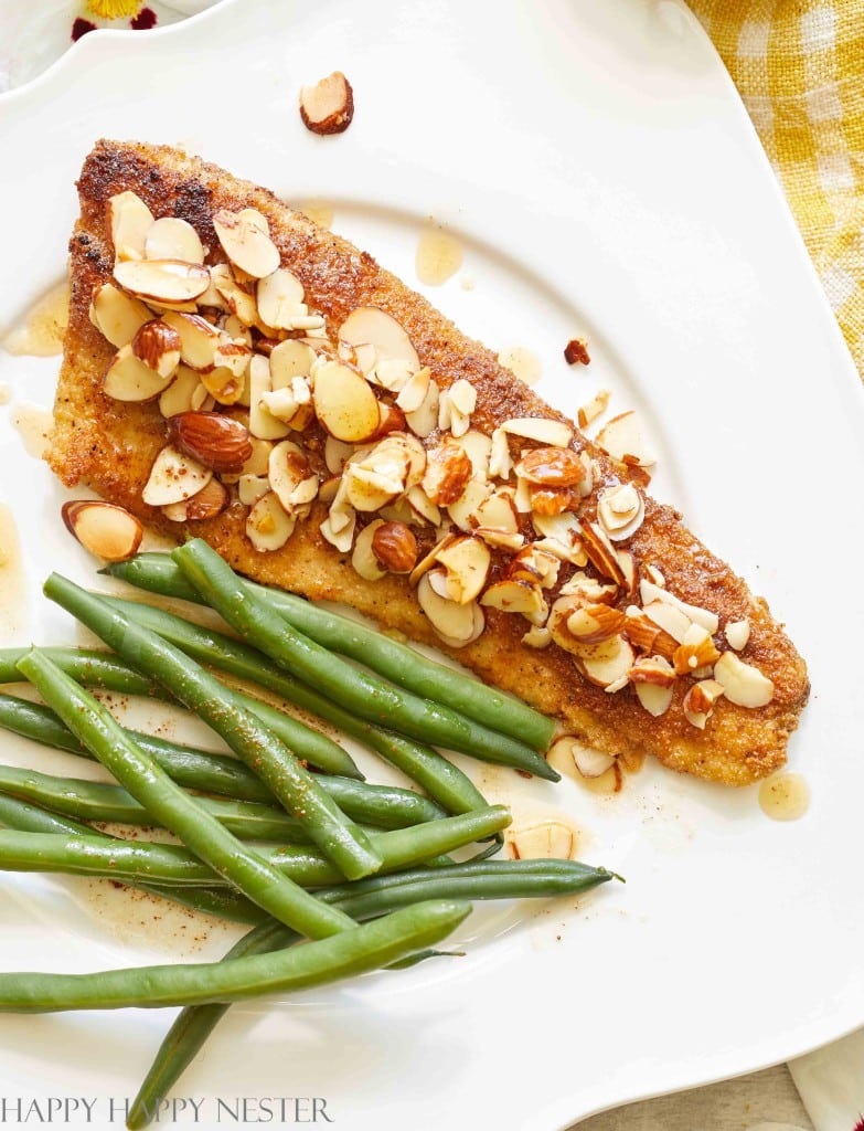 a close look at pan fried trout almondine covered with toasted almonds alongside some green beans