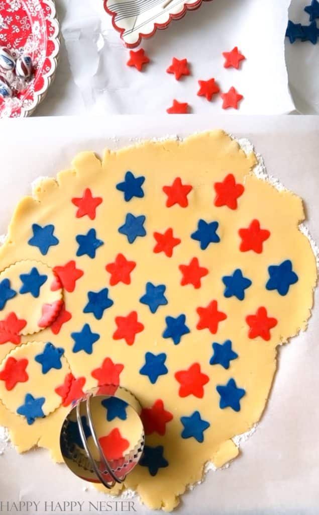 sugar cookie dough rolled out with blue and red stars laid on top of the dough