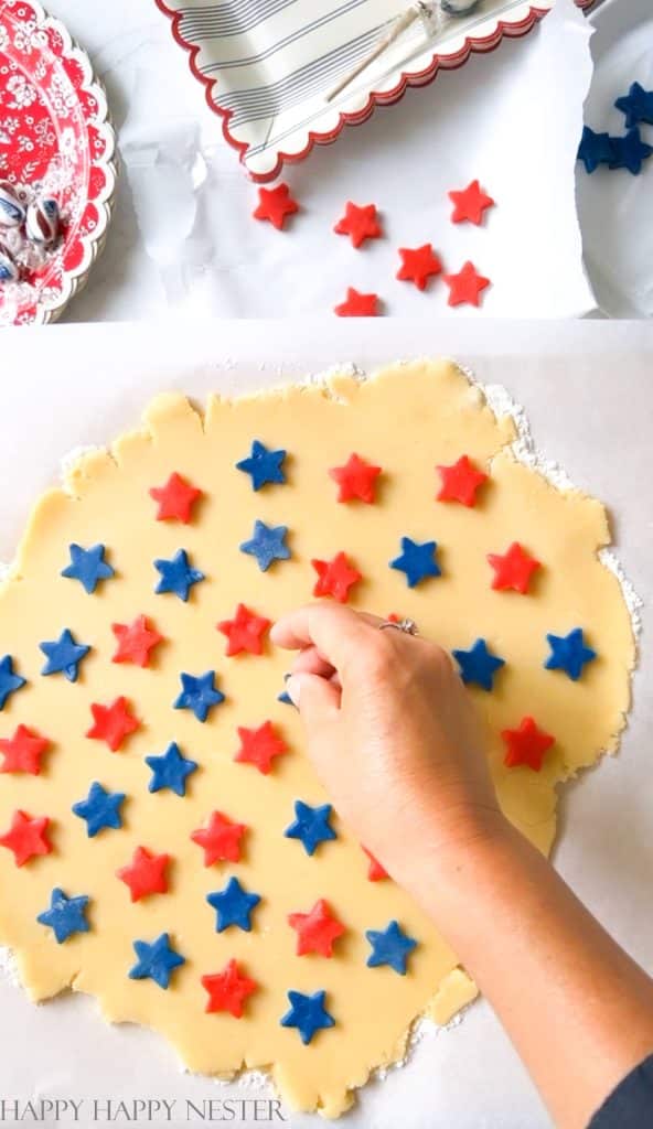 placing the cut out cookie dough stars on top of a rolled sugar cookie dough