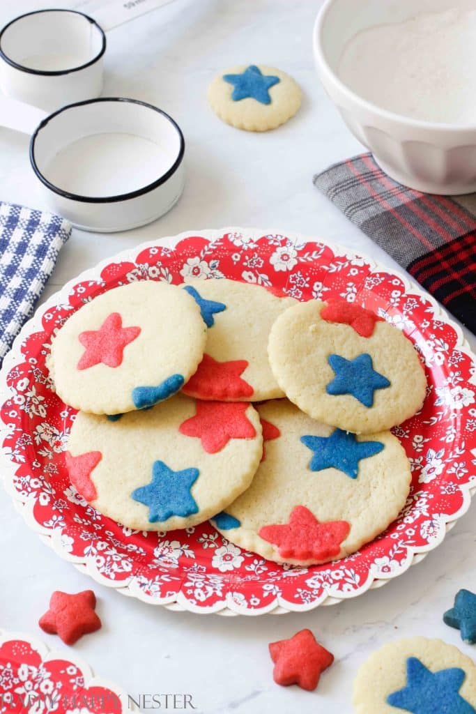 five 4th of july cookies with red and blue stars on a red paper plate