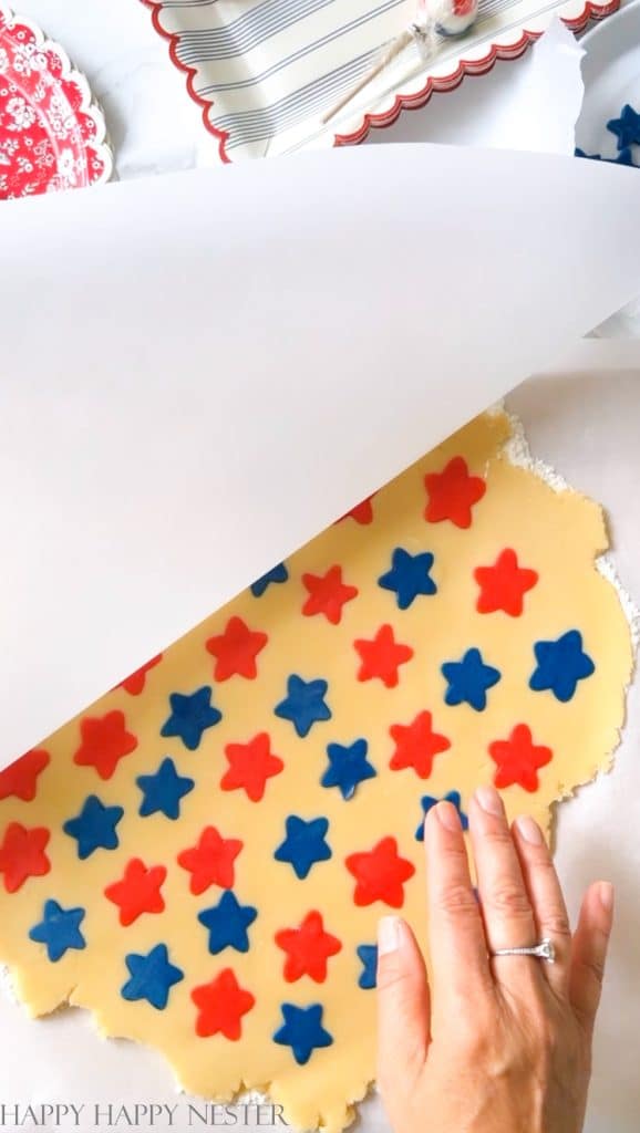 sugar cookie dough with red and white stars in between 2 sheets of parchment paper