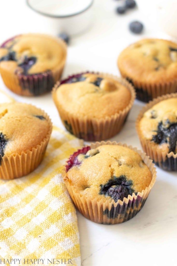 blueberry muffins on a table with yellow and white gingham towels