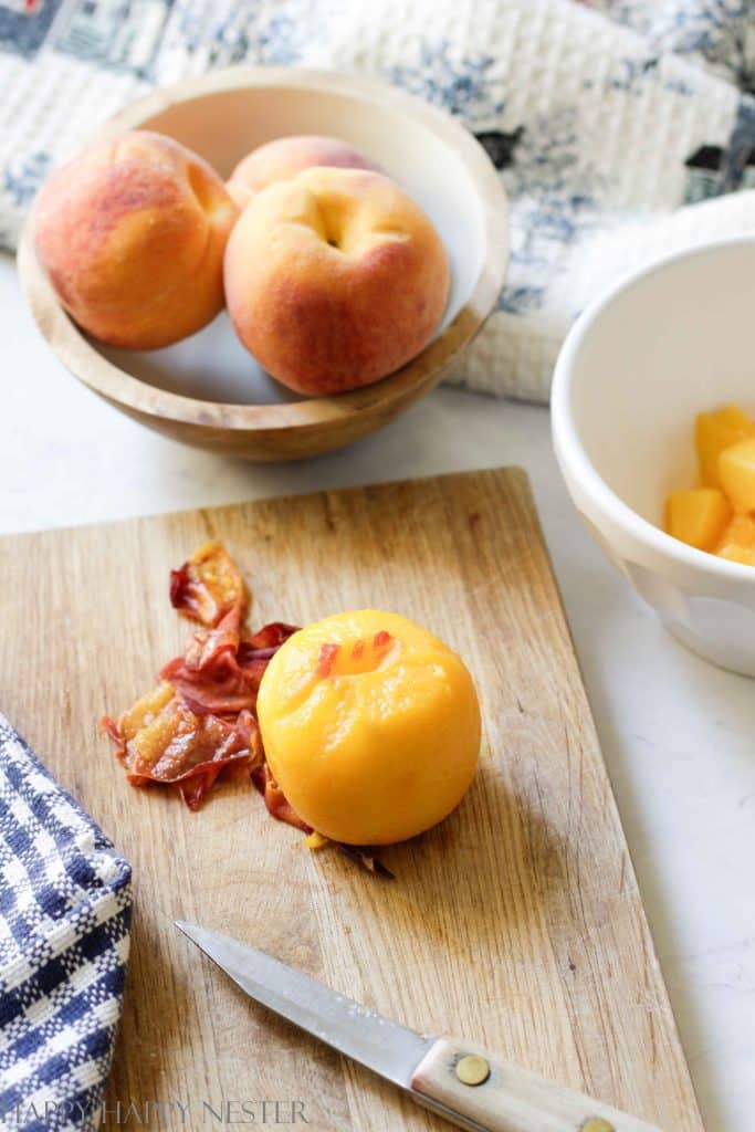 A peach that has been peeled that is sitting on a small wooden cutting board