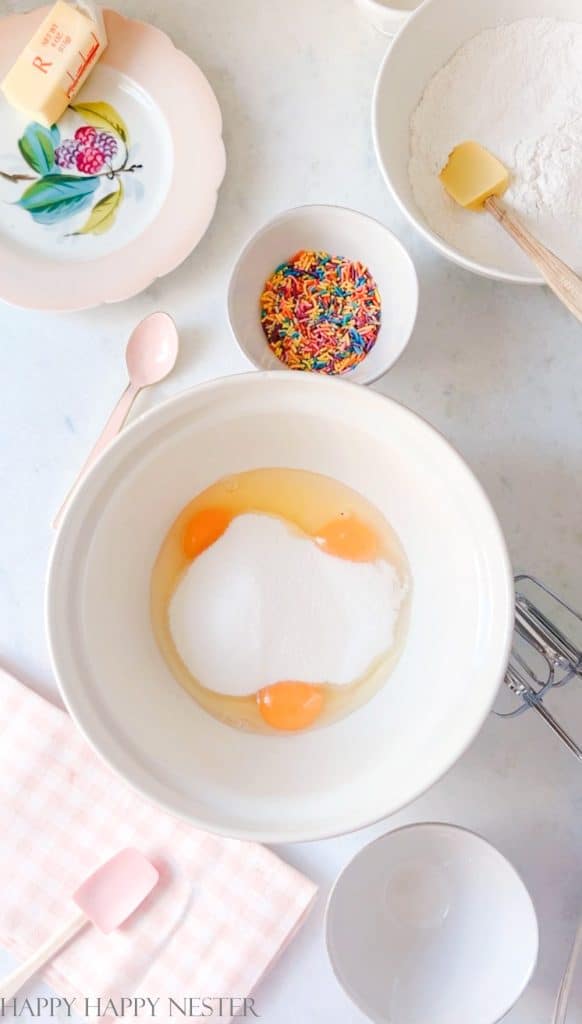A bowl with three eggs and sugar.