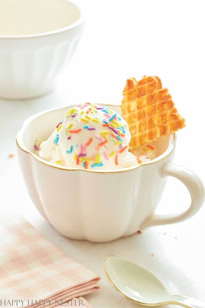 a cup of ice cream with rainbow sprinkles and pieces of pizzelles cookies