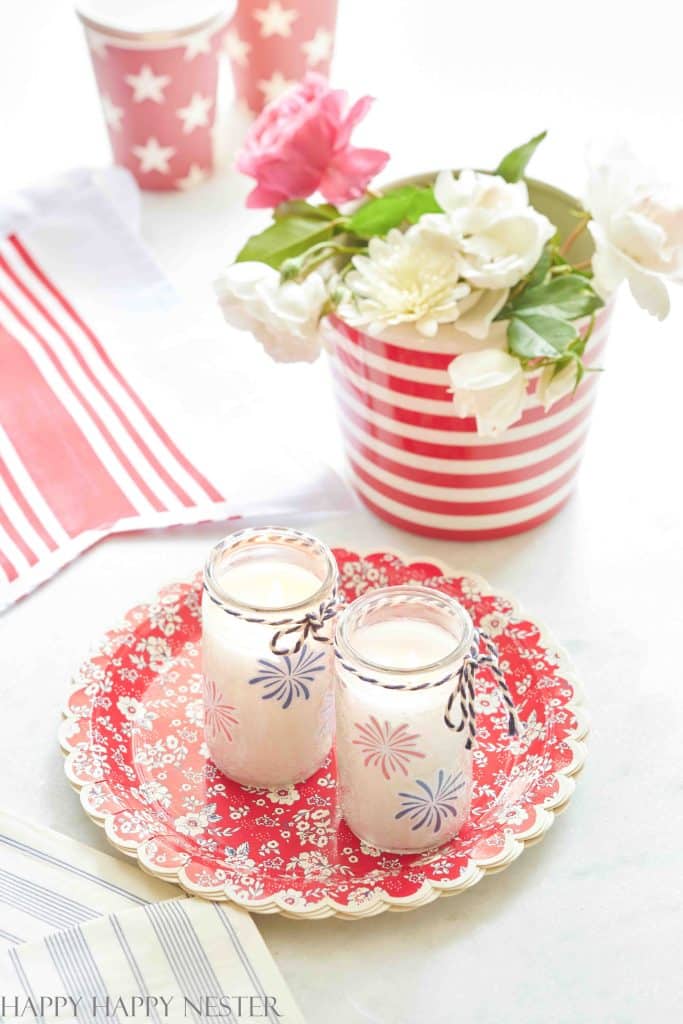 two decorated whit candles on a red patterned plate