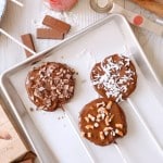 three chocolate covered apples slices on a white parchment lined baking tray