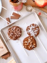 three chocolate covered apples slices on a white parchment lined baking tray