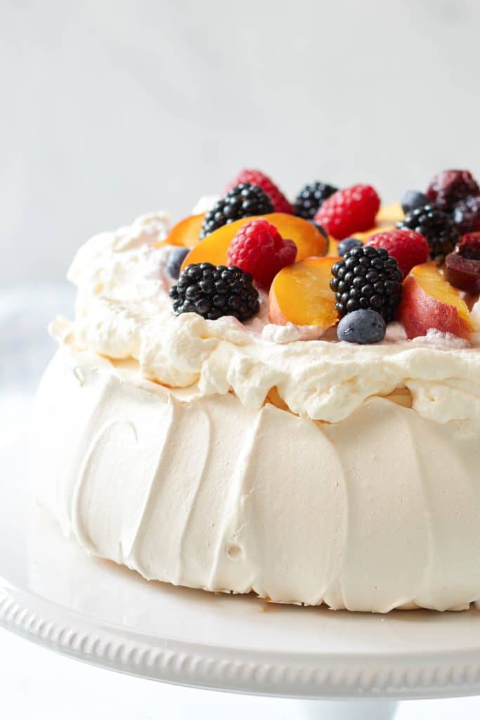 close up of the classic pavlova. meringue on bottoms and whip cream and fruit on top